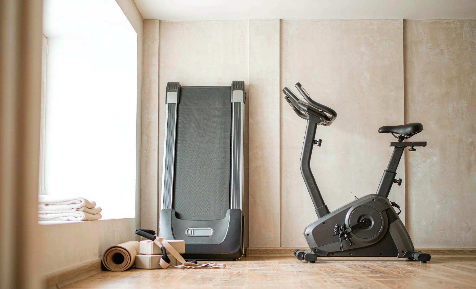 Treadmill, exercise bike and yoga accessories in a bright room