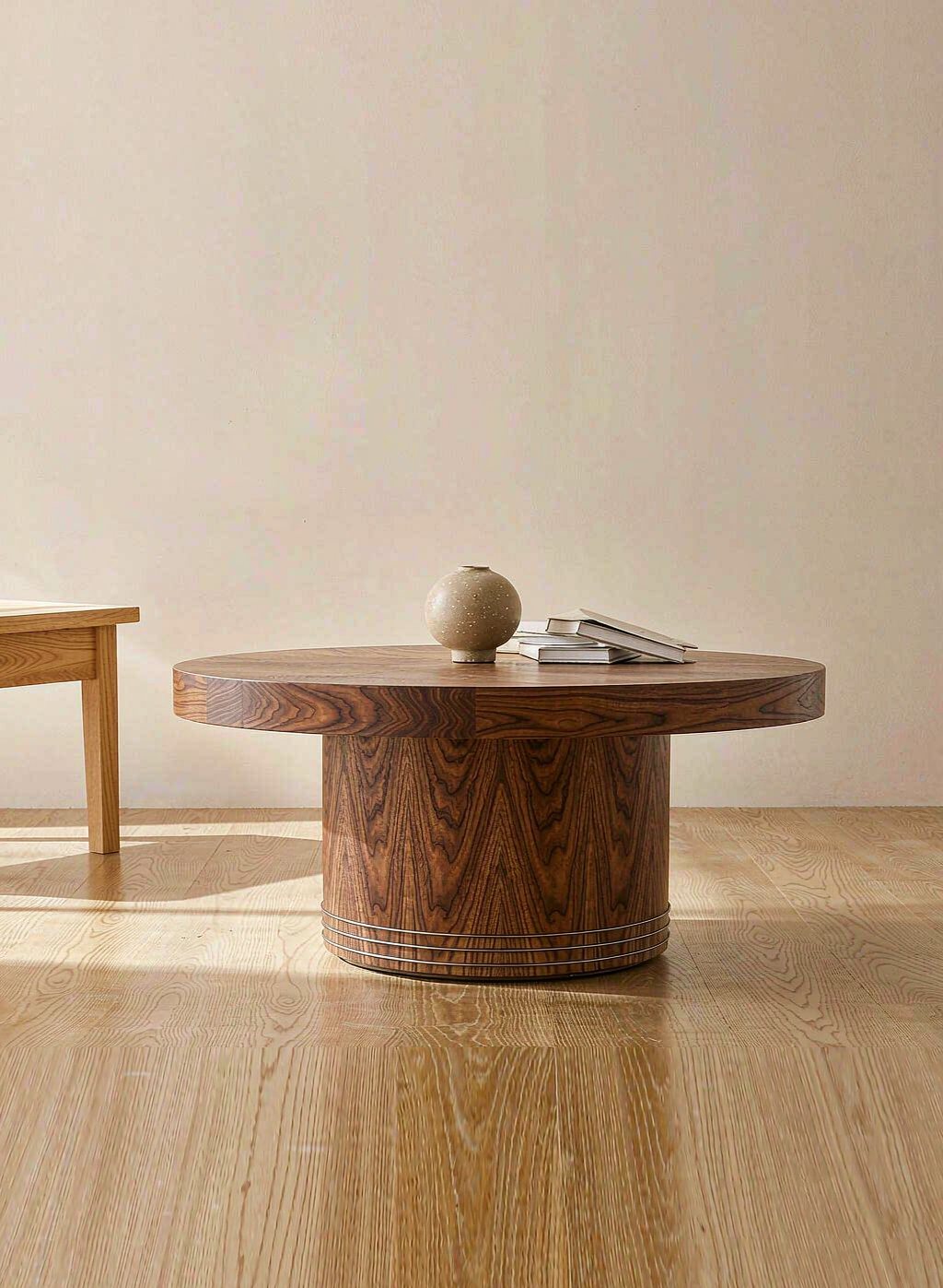 Round walnut coffee table with a vase and books