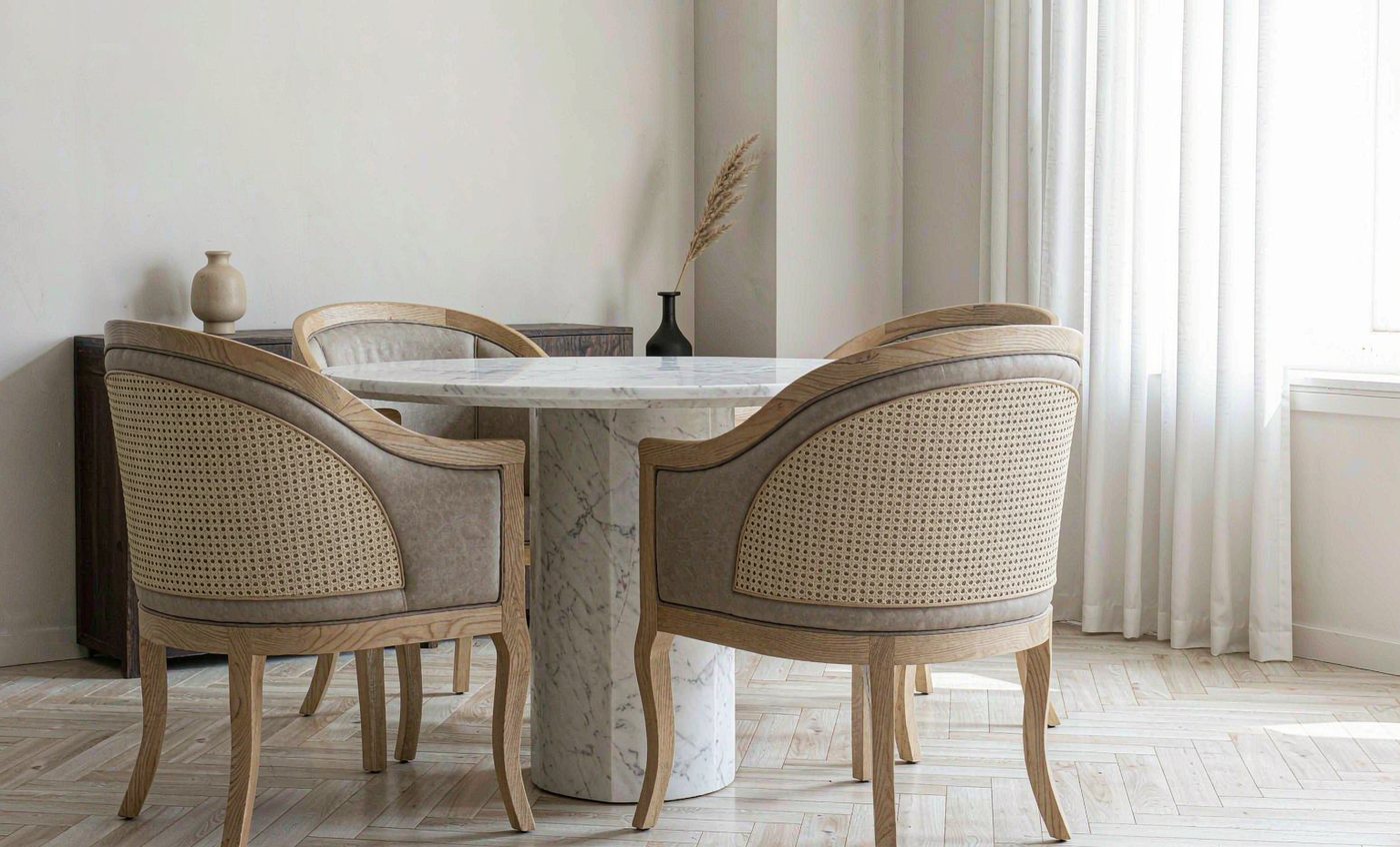 Round marble-top dining table with four cane-back upholstered chairs