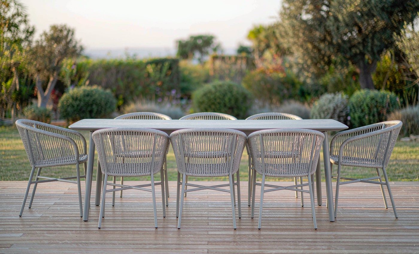 Outdoor dining table with six rope-weave chairs on a deck